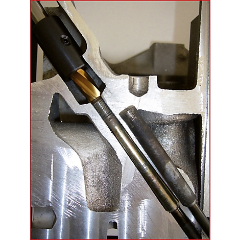 Nahaufnahme einer Maschine mit Bohrer und Metallteilen. Der Bohrer dringt in das Metall ein.